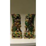 A pair of 18th/19th century Buddhist lions, the green beasts seated on 'spinach and egg' glazed