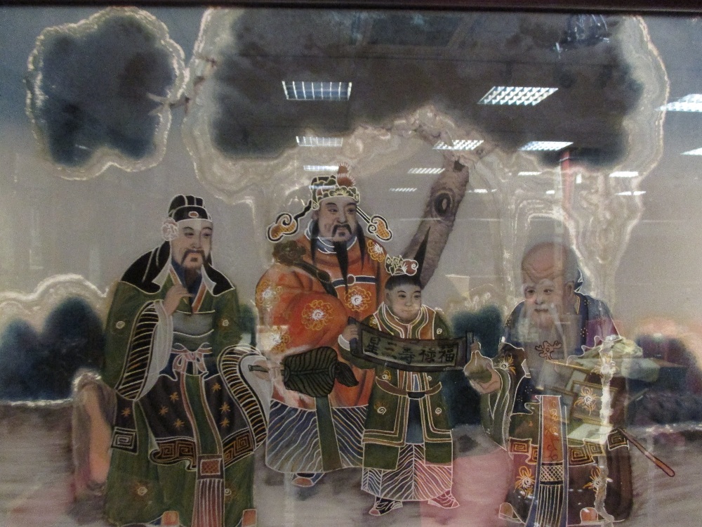 A reverse glass painting of a trio of dieties Shou, Lu and Fu with a boy attendant