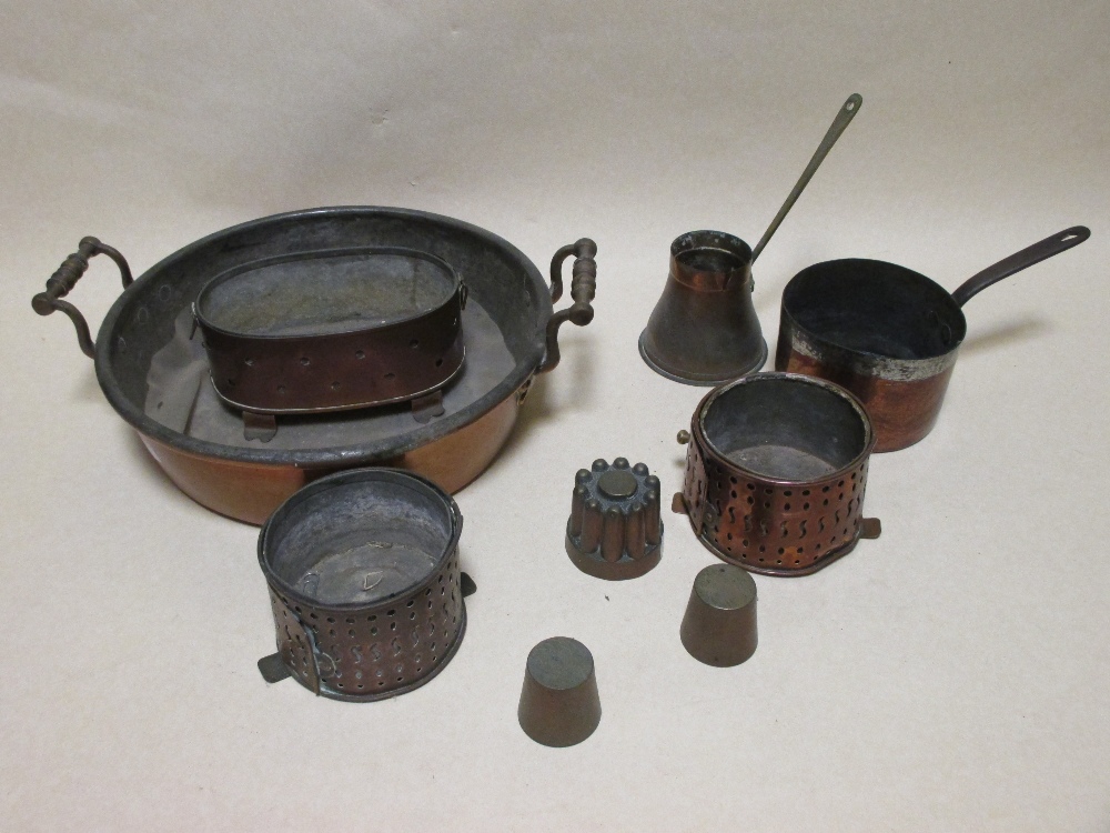 A collection of copper kitchen wares including a two handled pan, miniature jelly mould and other