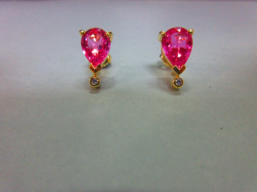 A pair of pink sapphire, diamond and 18ct gold earstuds, each post headed by a three claw set pear