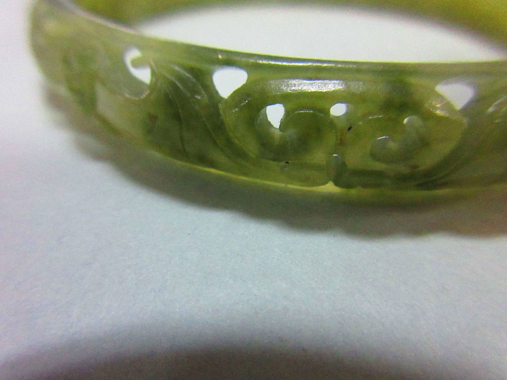 A carved jade bangle, the mottled light green jade of convex profile, pierced and carved with - Image 3 of 5