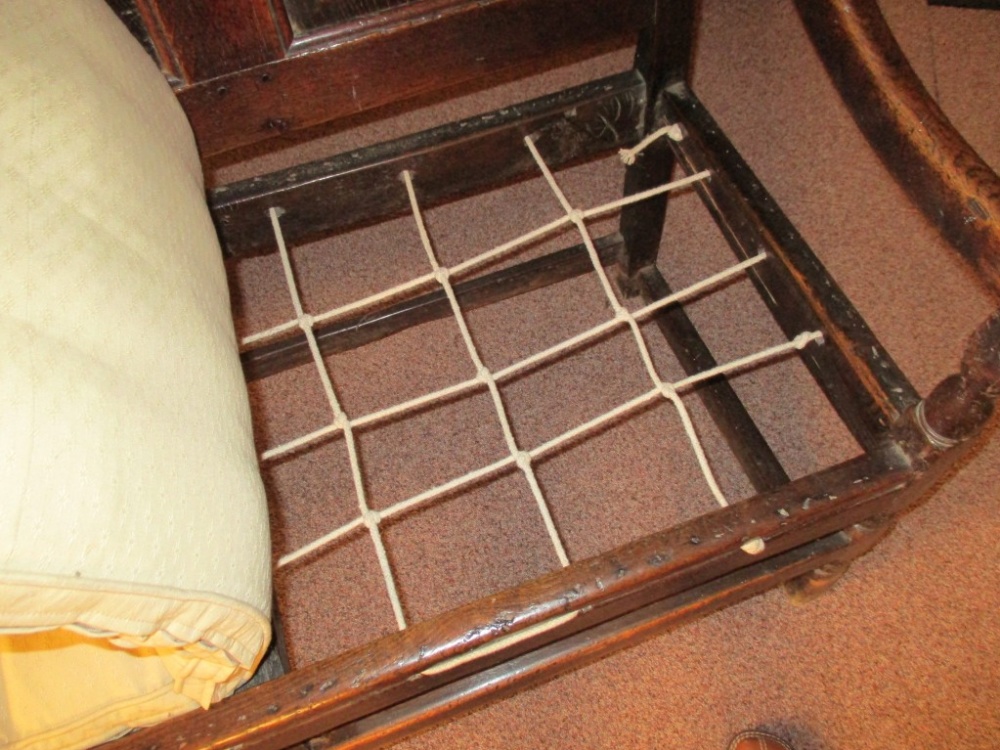 An early 18th century oak panelled settle, with open arms, strung seat and loose cushion, on - Image 3 of 4