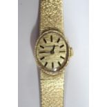 By Longines - a lady's 9ct gold cased wristwatch, the oval gold coloured dial with baton numerals,