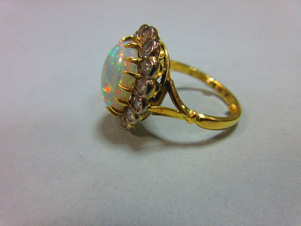 An opal and diamond cluster ring, the oval cabochon opal, displaying a rainbow range of fire, claw - Image 3 of 5