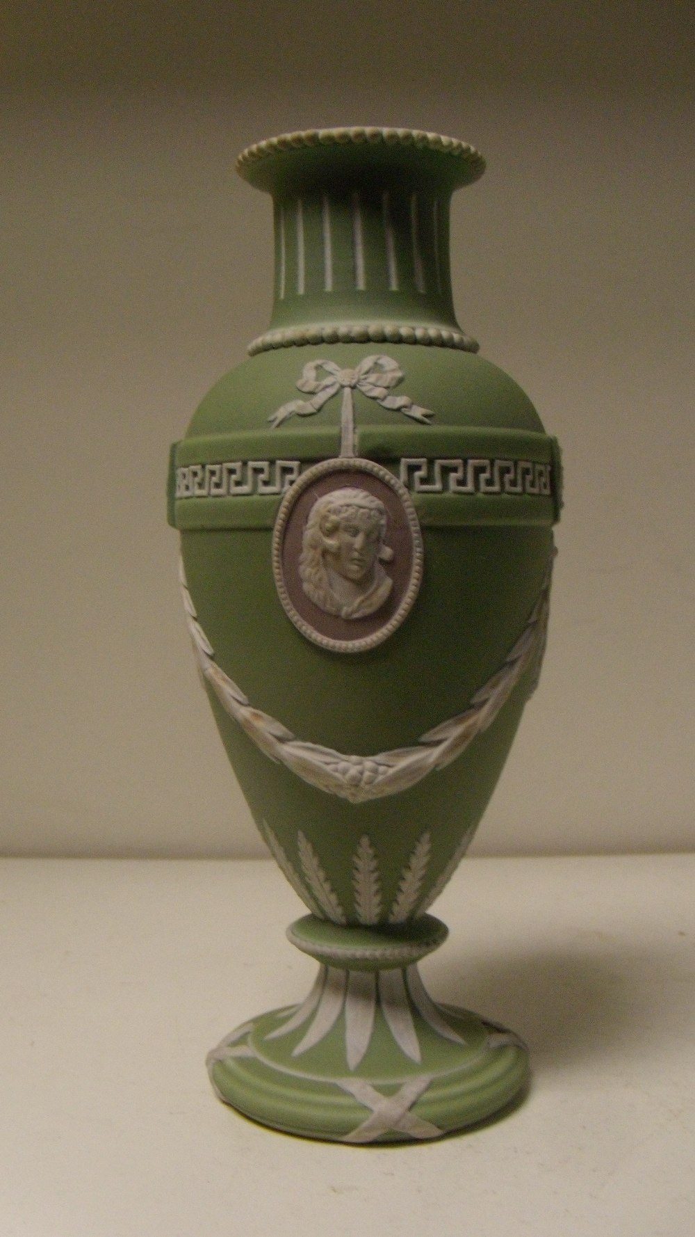 A Wedgwood three colour jasper vase, the green ovoid body with two classical profiles in white on