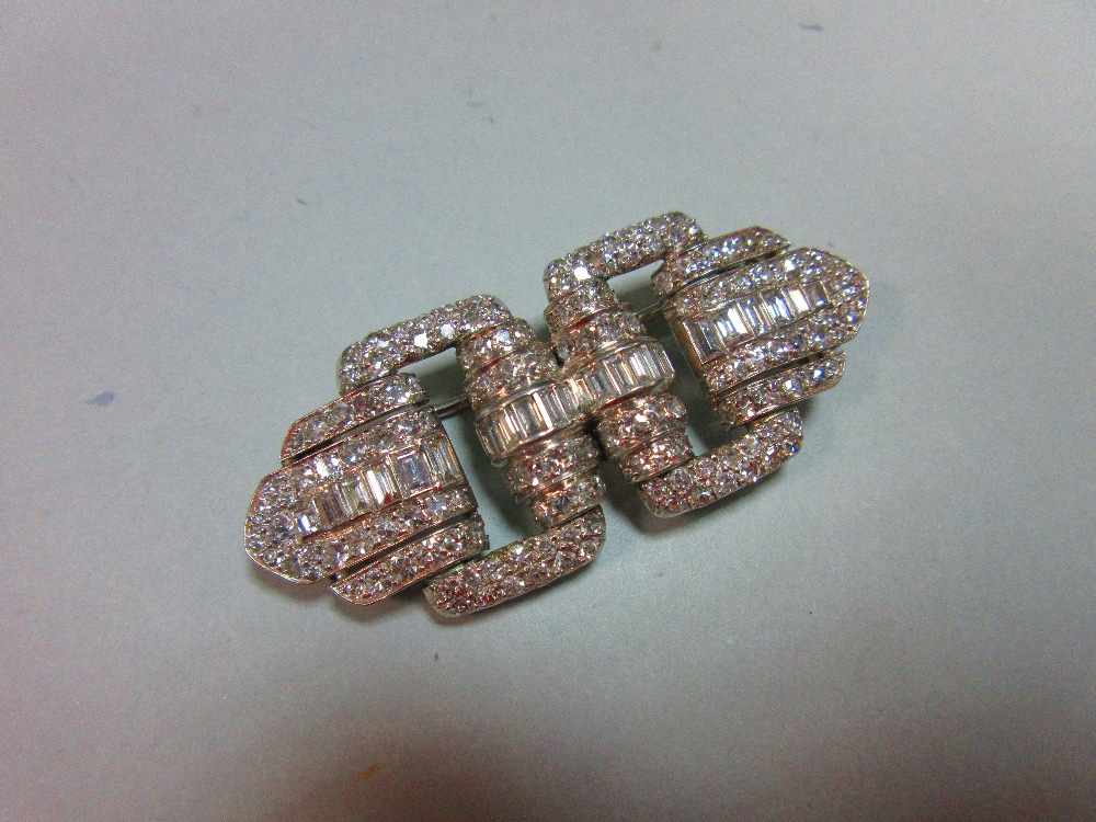 A French art deco odeonesque diamond and platinum brooch, of pierced double buckle form, with a