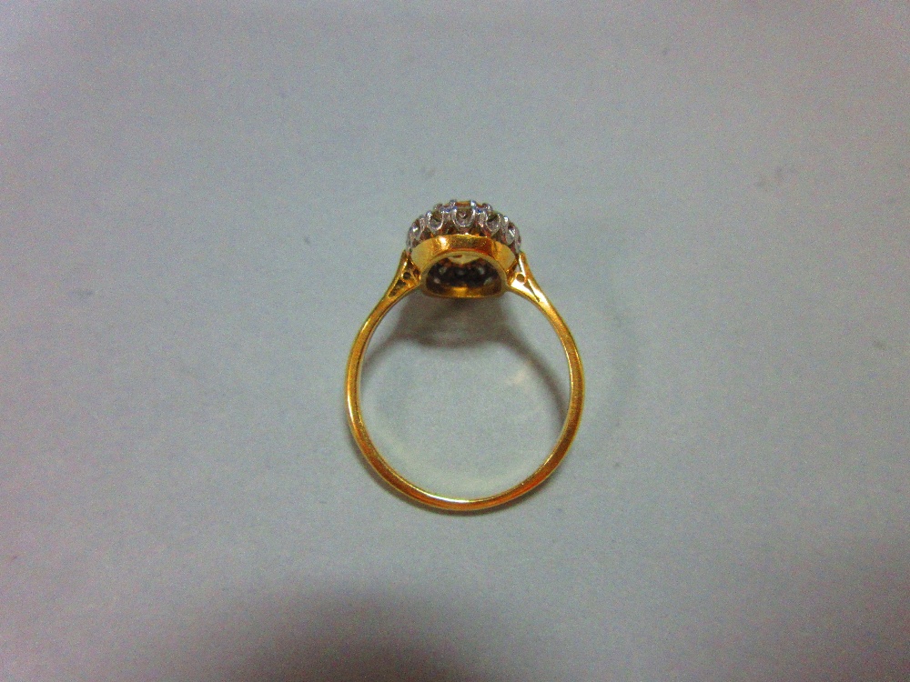 A topaz and diamond cluster ring, the oval cut light orange-brown topaz claw set in a border of - Image 5 of 5
