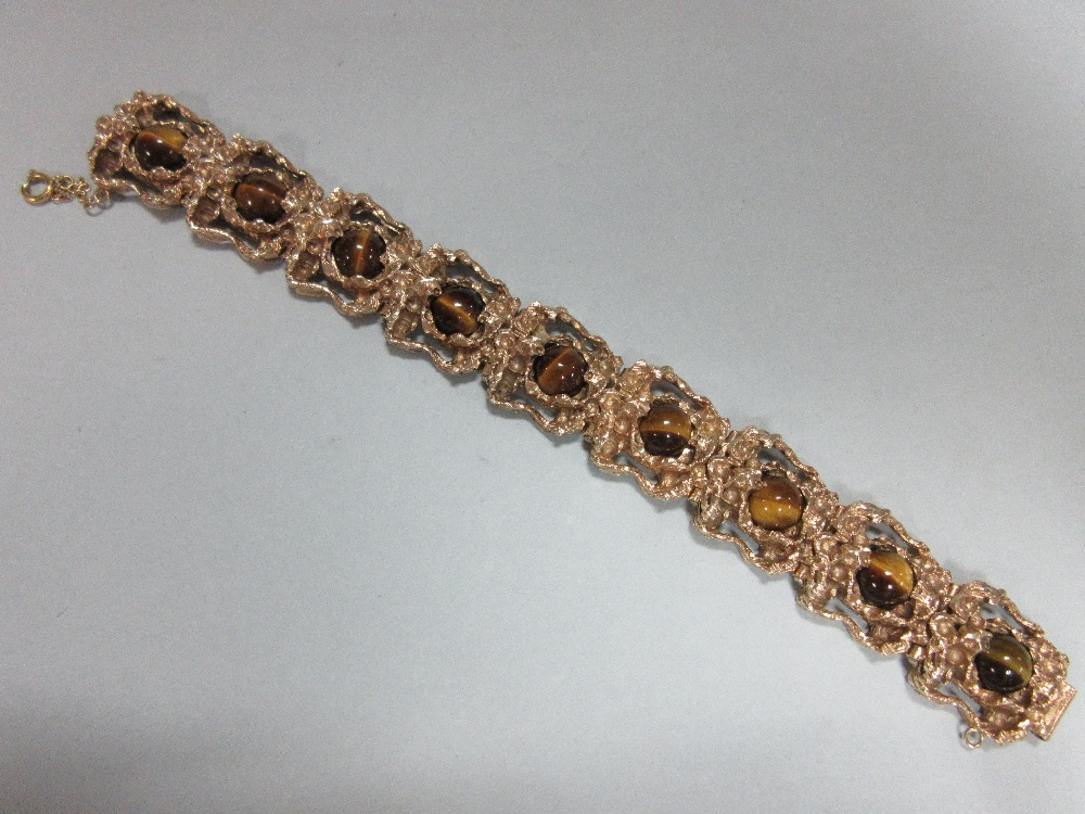 A 9ct gold and tiger's eye bracelet, the nine pierced, deeply-modelled, heavy cast links each set