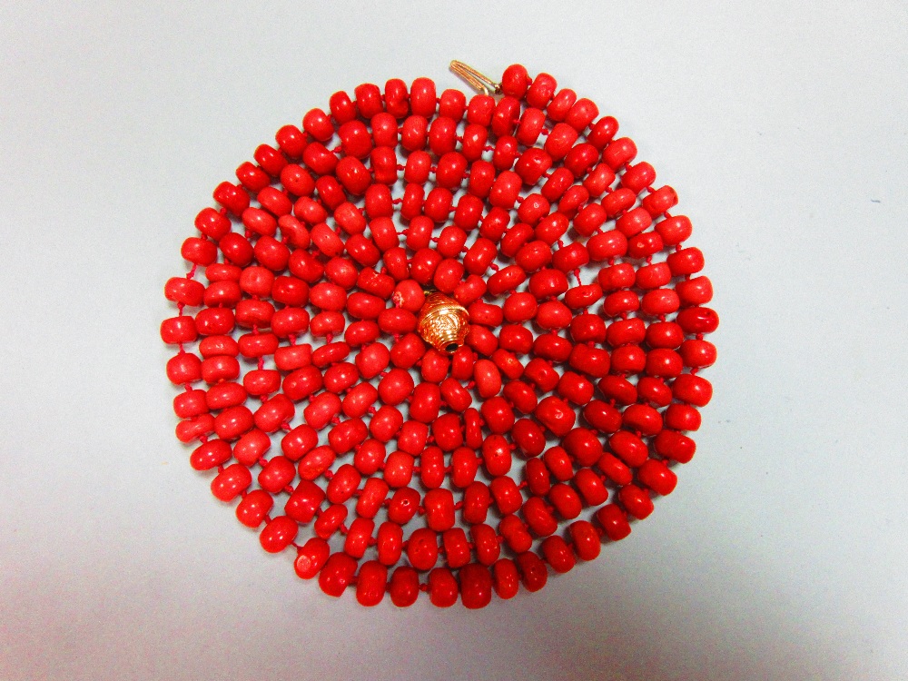 A long red coral bead necklace, the individually-knotted tyre shaped coral beads of approximately