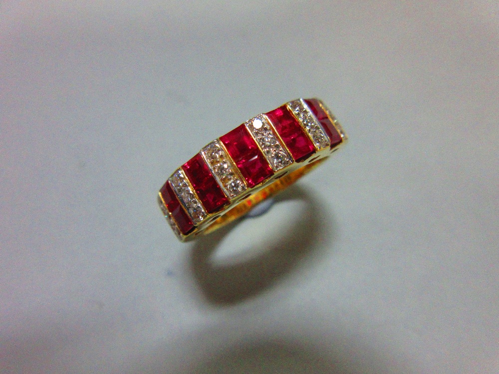 A contemporary 18ct gold ruby and diamond band ring, set all around the front with alternating