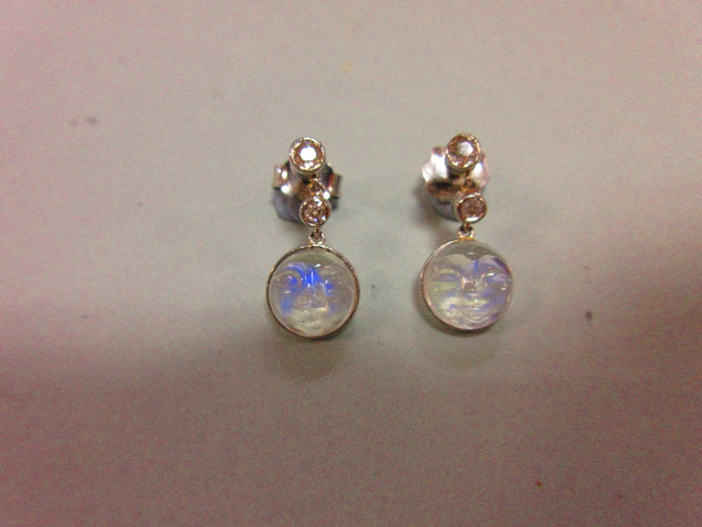 A pair of 'man in the moon' carved moonstone and diamond earpendants, designed as an articulated