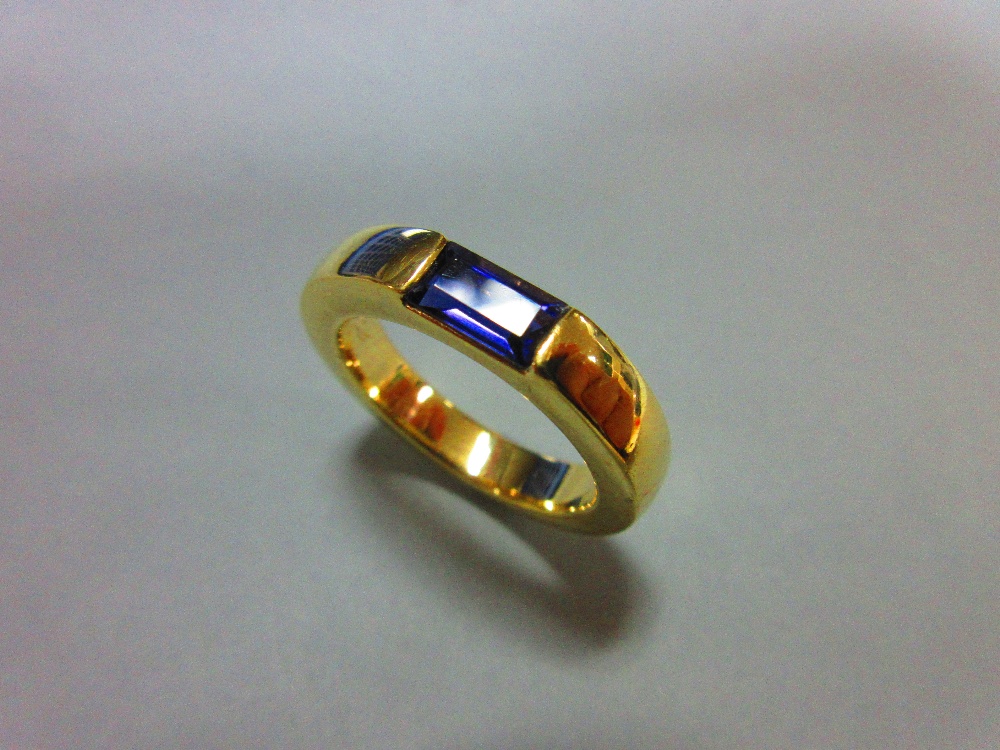 A contemporary iolite ring by Quinn, the rectangular step cut iolite tension set horizontally in a
