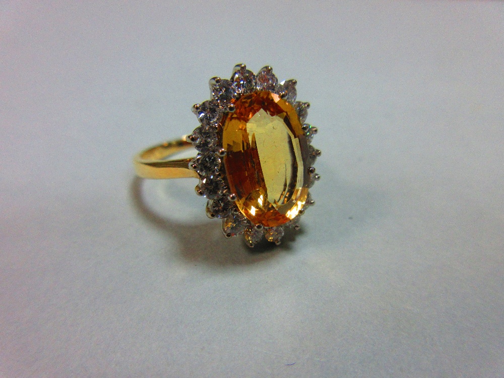 A topaz and diamond cluster ring, the oval mixed cut golden topaz claw set to a border of eighteen - Image 5 of 5