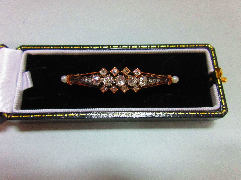 An antique diamond and pearl brooch, designed as a pierced and tapered slightly convex line with