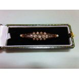 An antique diamond and pearl brooch, designed as a pierced and tapered slightly convex line with