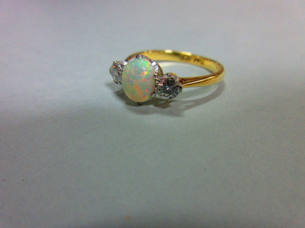 An opal and diamond three stone ring, the oval cabochon opal claw set between two round brilliant - Image 2 of 4