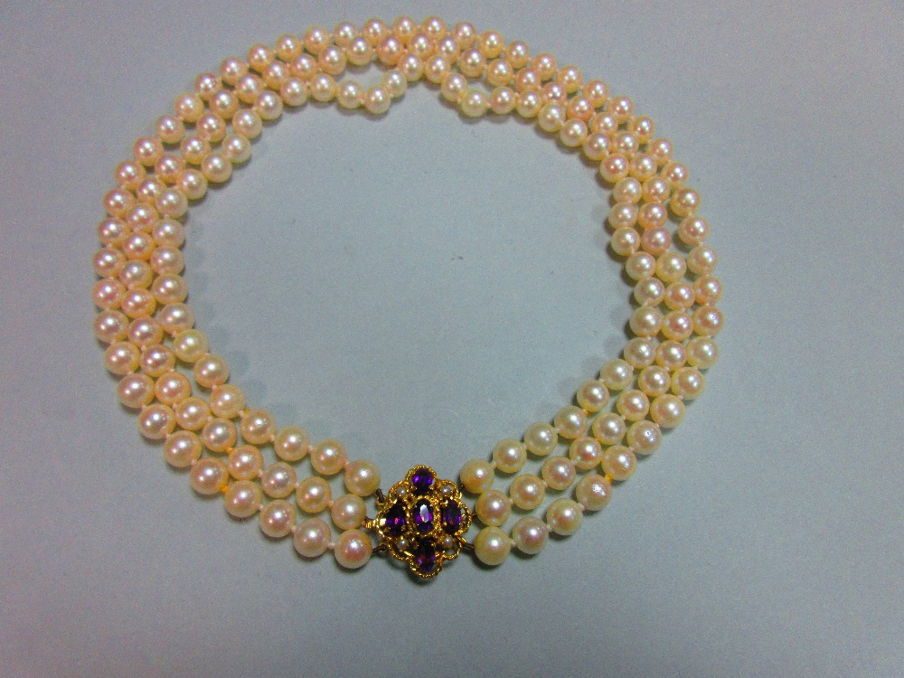 A three row pearl necklace with gold, amethyst and seed pearl clasp, the uniform 7.5-8mm cultured