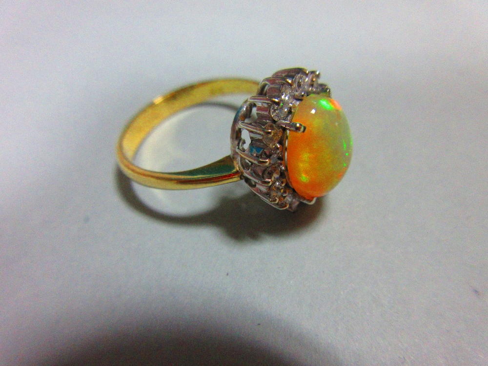 An opal and diamond cluster ring, the oval cabochon opal, displaying vivid predominently green and - Image 2 of 6