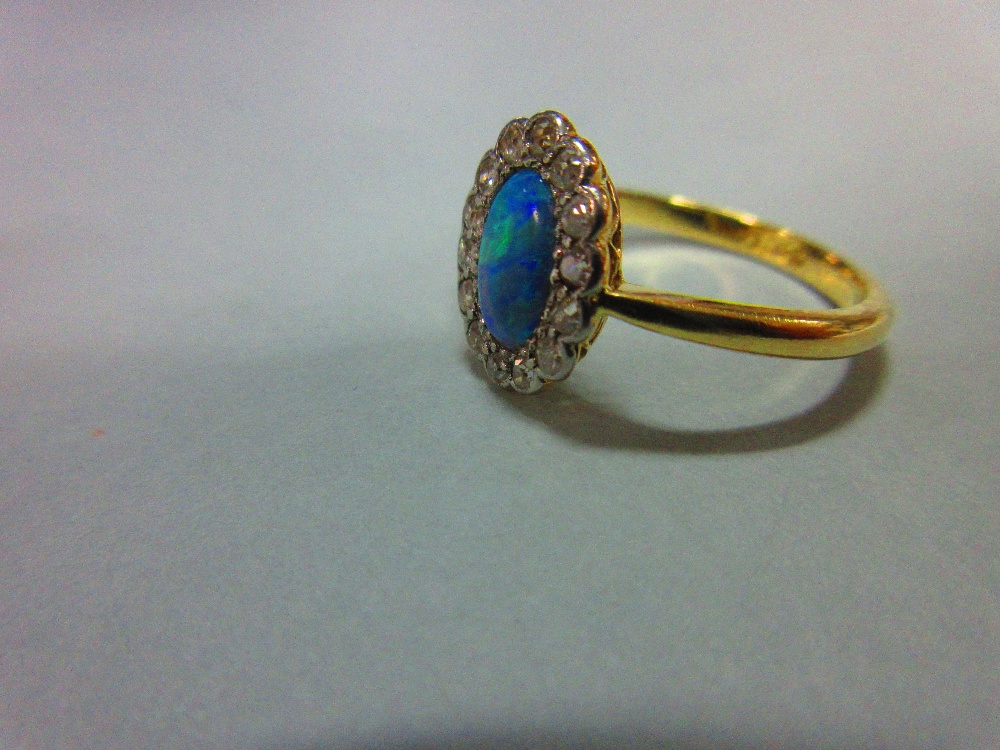 An oval opal and diamond cluster ring, the oval cabochon opal in a petal-edge border of single cut - Image 3 of 5