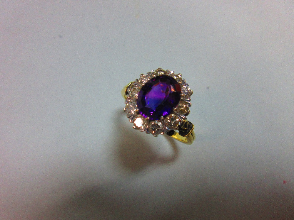 An amethyst and diamond cluster ring, the oval mixed cut rich purple amethyst claw set in a border