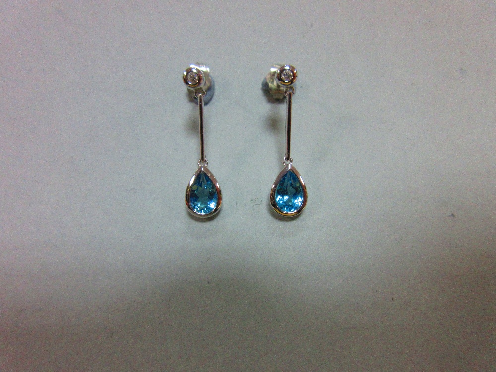 A pair of blue topaz, diamond and white gold earpendants, each post headed by a collet set round