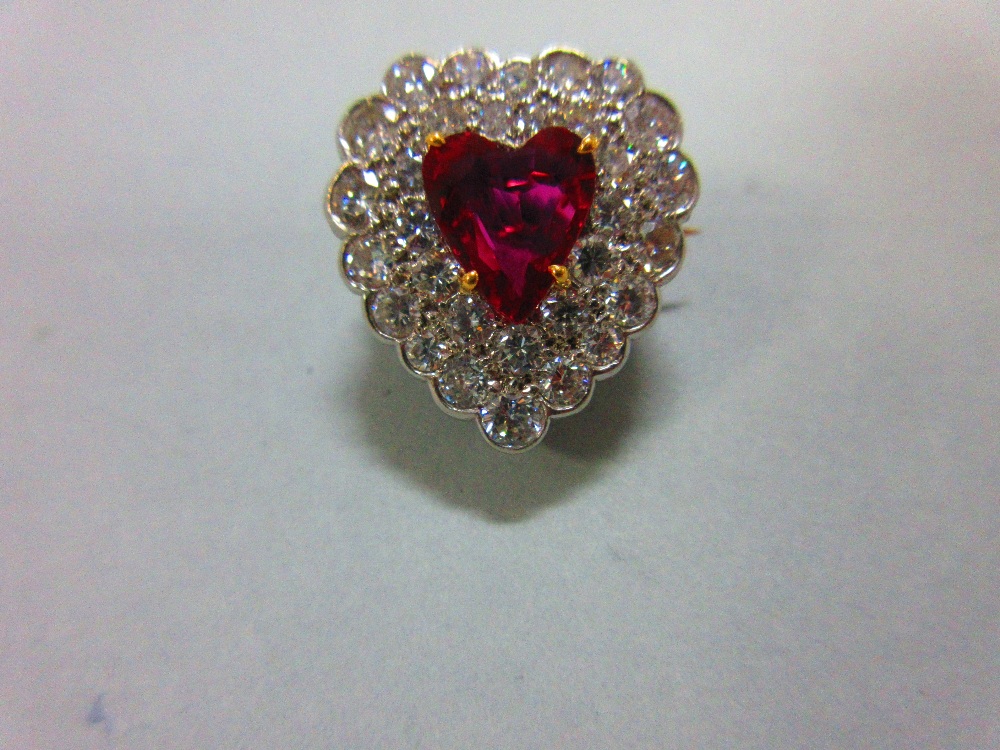 A ruby and diamond heart shaped brooch, with a heart cut ruby within a double row of pavé set