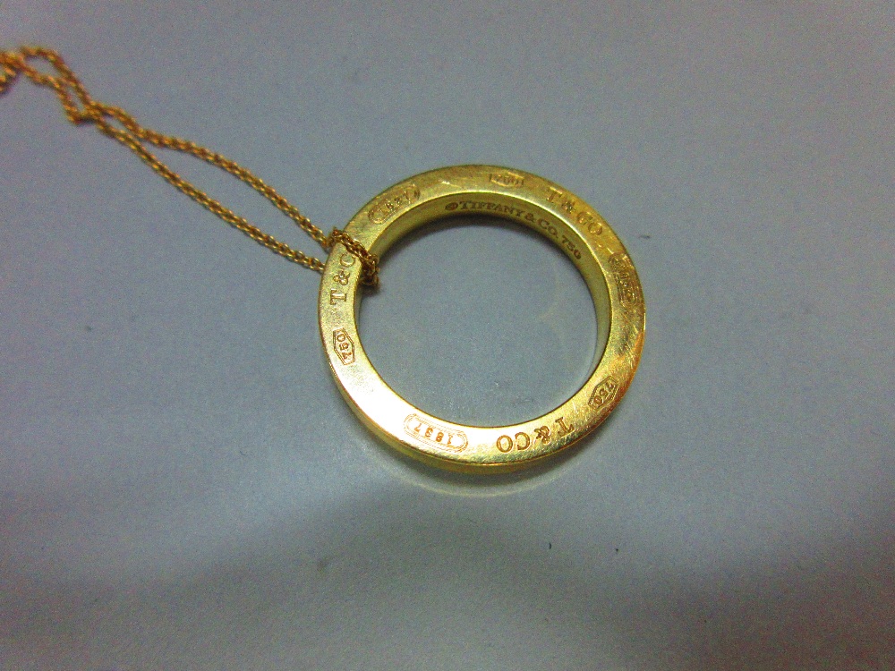 A Tiffany gold ring pendant and chain, the solid ring, diameter 2.6cm, with concave edge, and