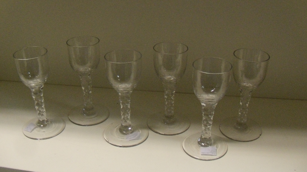 A set of six 18th century wines, each with cylindrical bowls rounding into the facetted stems on