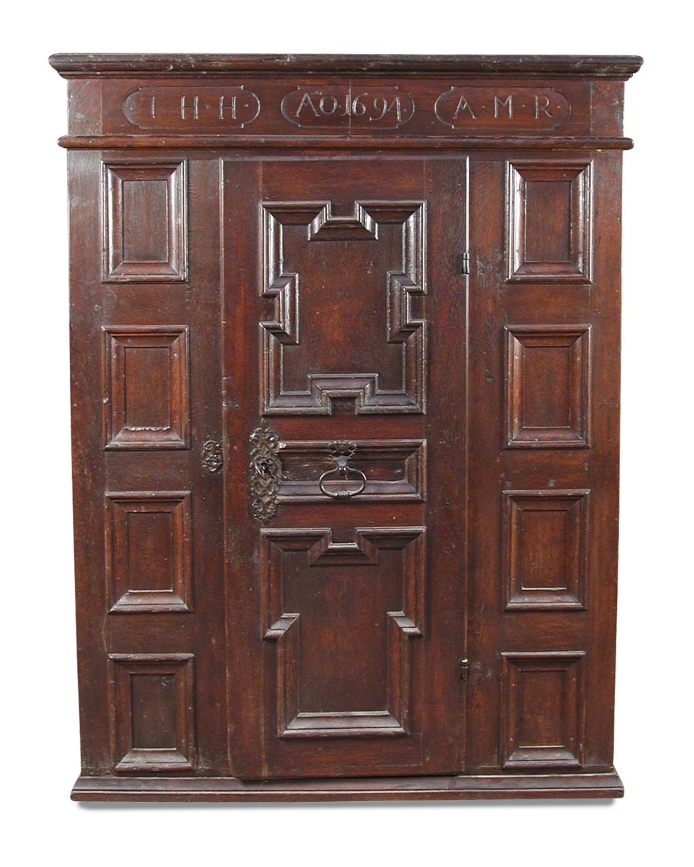 A 17th century Flemish oak panelled armoire, the frieze carved with monogram and date 1694, a