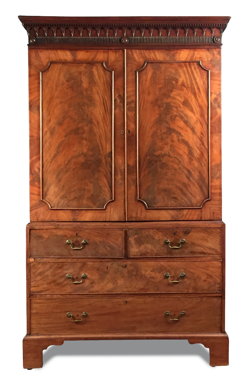 A George III mahogany linen press, with dentil and corbel moulded frieze, panelled doors enclosing