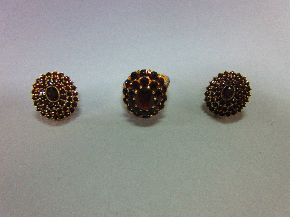 A Bohemian garnet cluster ring and a pair of matched earstuds, the ring with an oval cut pyrope