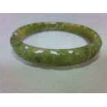 A carved jade bangle, the mottled light green jade of convex profile, pierced and carved with