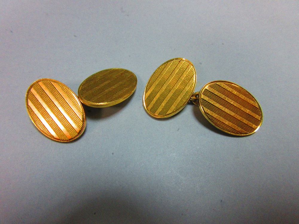 A pair of 18ct gold double-ended cufflinks, each oval end with incised striped decoration, chain