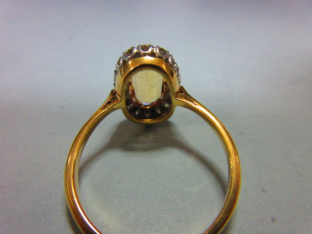 A topaz and diamond cluster ring, the oval cut light orange-brown topaz claw set in a border of - Image 4 of 5