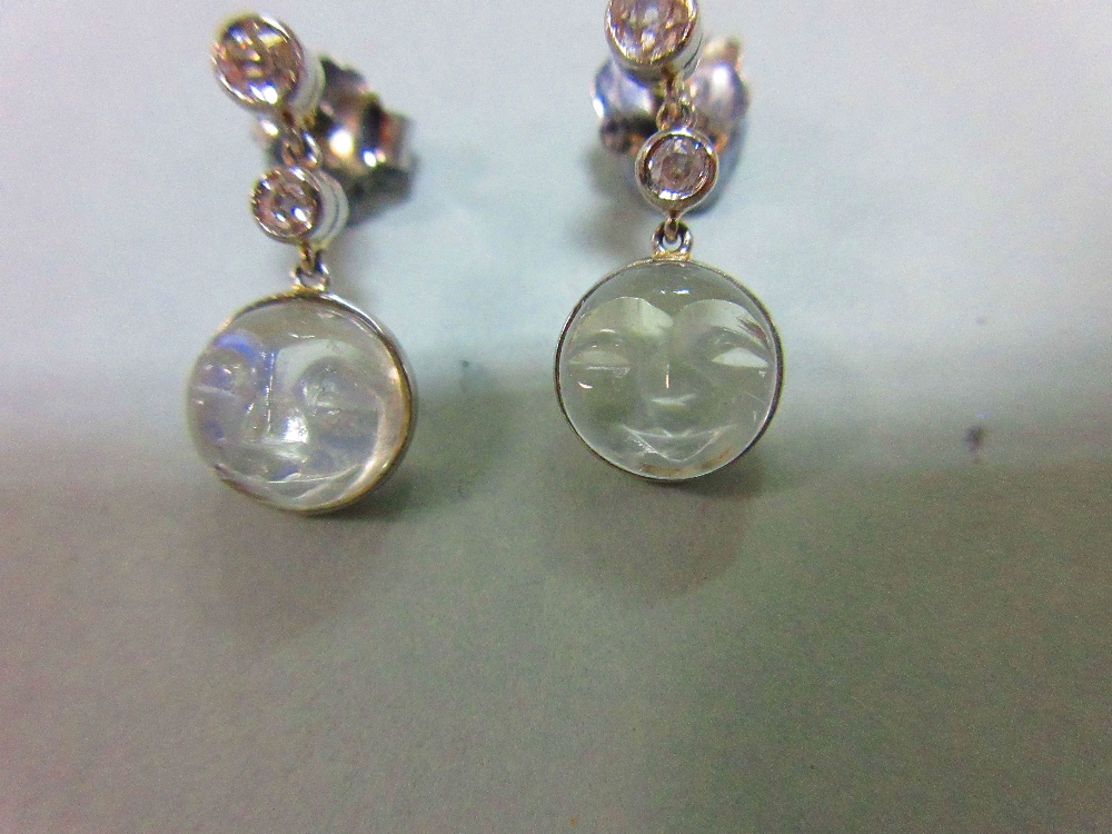 A pair of 'man in the moon' carved moonstone and diamond earpendants, designed as an articulated - Image 3 of 5