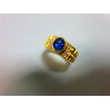 A sapphire and diamond ring, the oval cut intense blue sapphire in a raised collet between lines