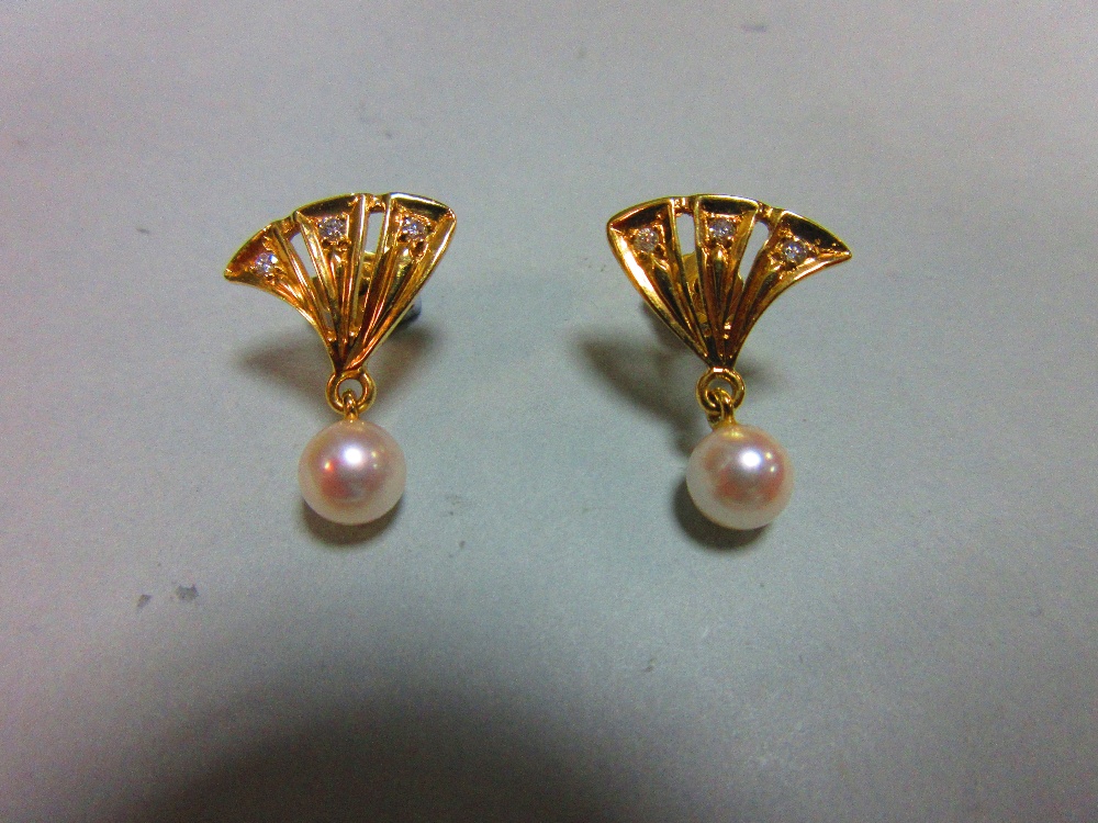 A pair of pearl and diamond earstuds, each with a pierced triangular fan motif set with three