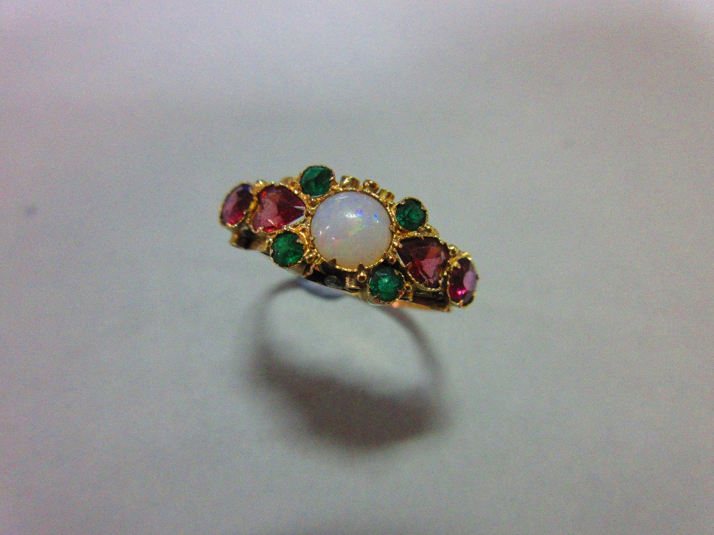 A Victorian opal and gemset ring in 15ct gold, the round cabochon opal between heart cut and round