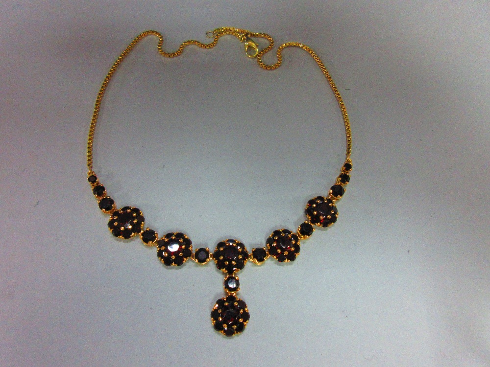 A Bohemian garnet cluster necklace, composed of five flowerhead clusters of round cut garnets,