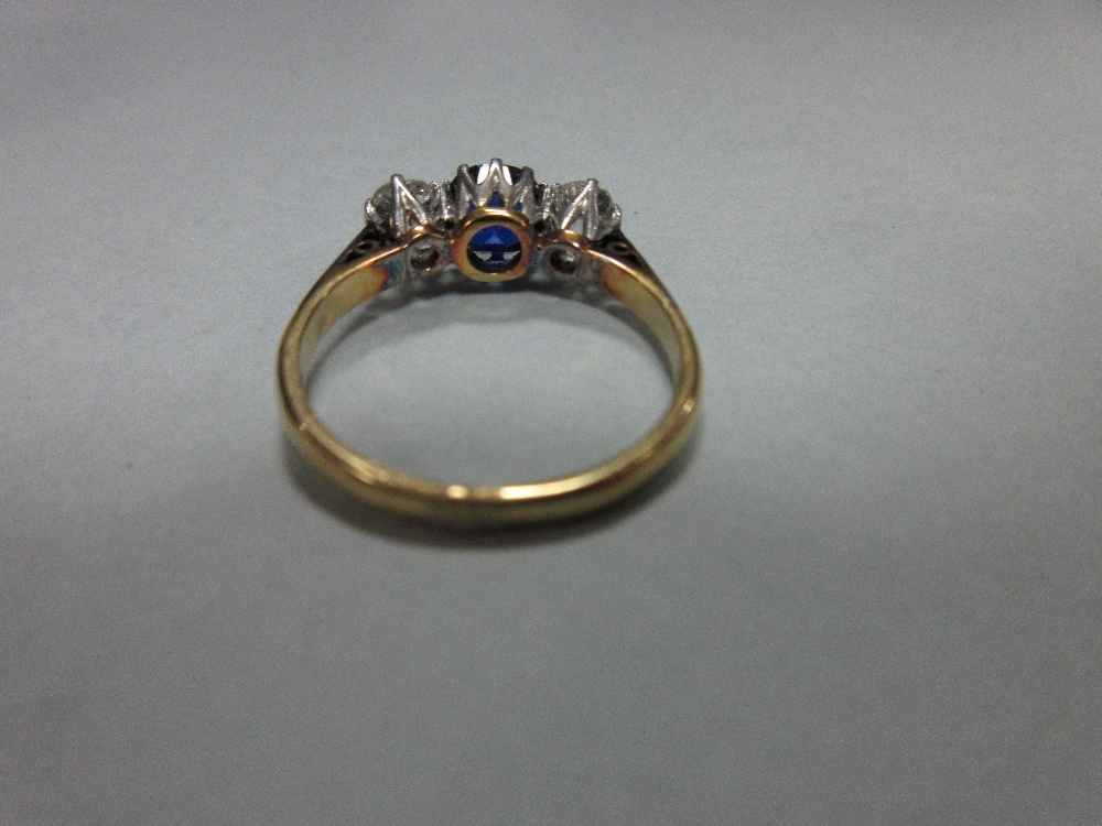 A three stone sapphire and diamond ring, claw set with a round cut royal blue sapphire between old - Image 5 of 7