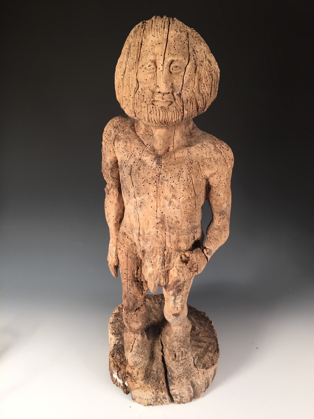 A Mediaeval style carved wood figure, possibly of Adam, the bearded figure naked with his left