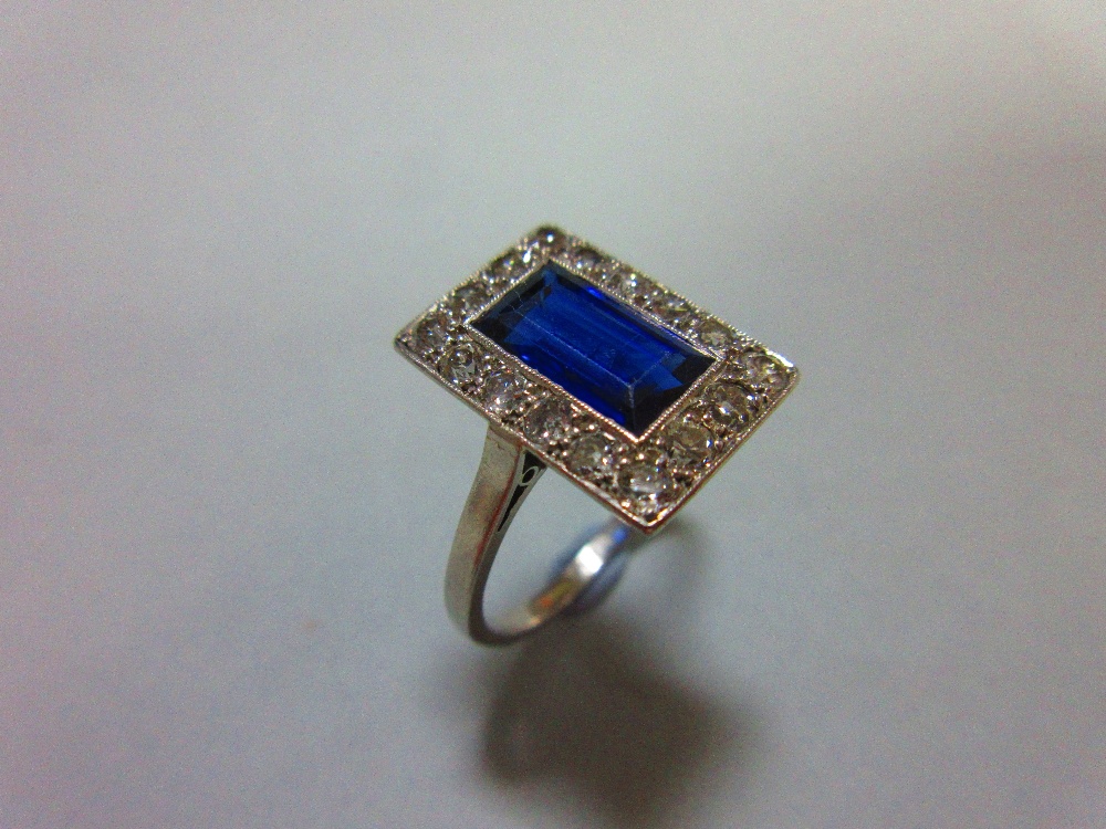 A mid 20th century sapphire and diamond ring, the rectangular step cut royal blue sapphire in a