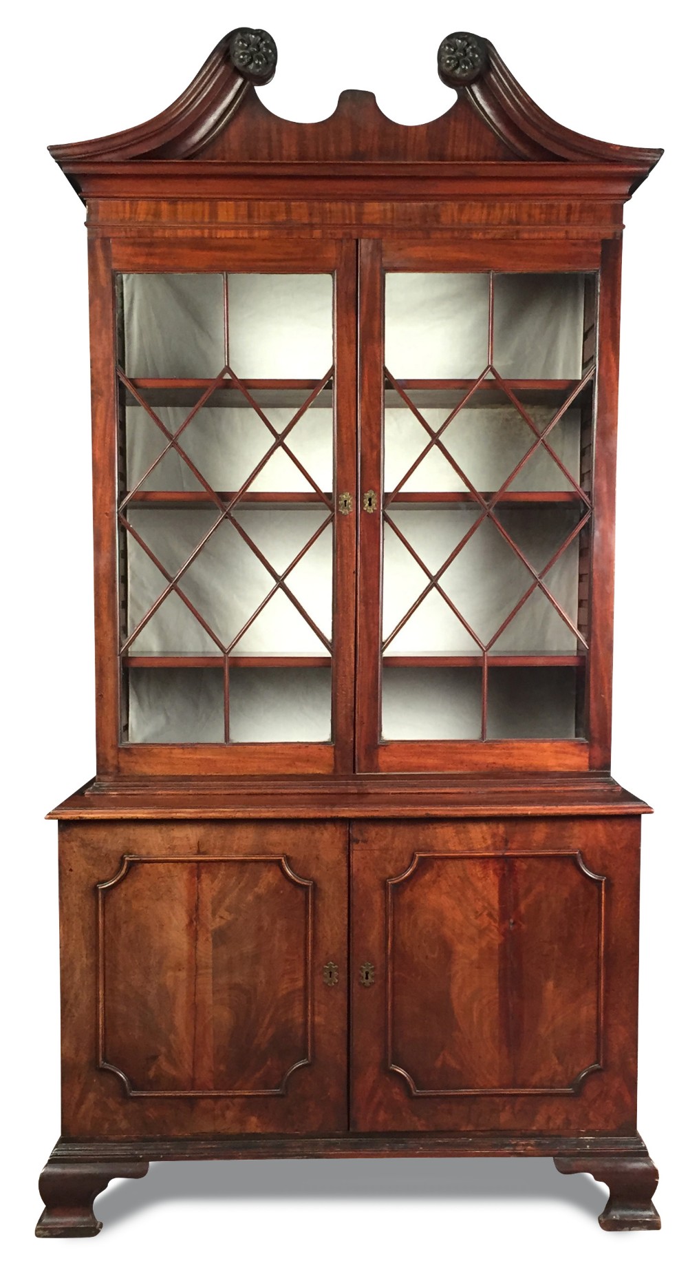 An early George III mahogany cabinet, with swan neck pediment above two glazed doors and panelled