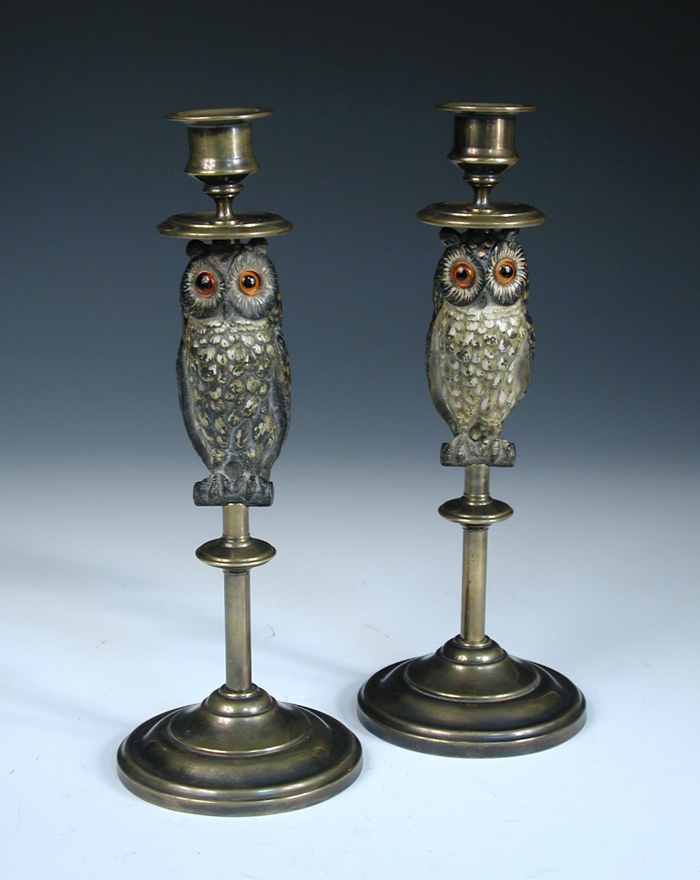 A pair of late 19th century brass candlesticks, the columnular stems set with a figure of a cold