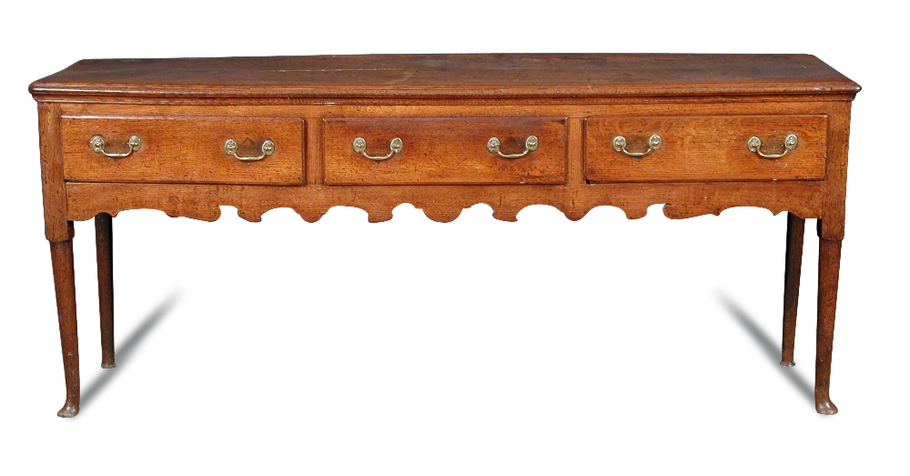 A George III oak dresser base, fitted three drawers with brass handles, shaped fret carved apron