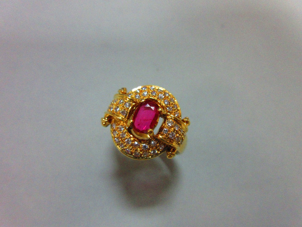 A red hardstone and diamond cluster ring, the oval cut red stone, believed to be a ruby, but not