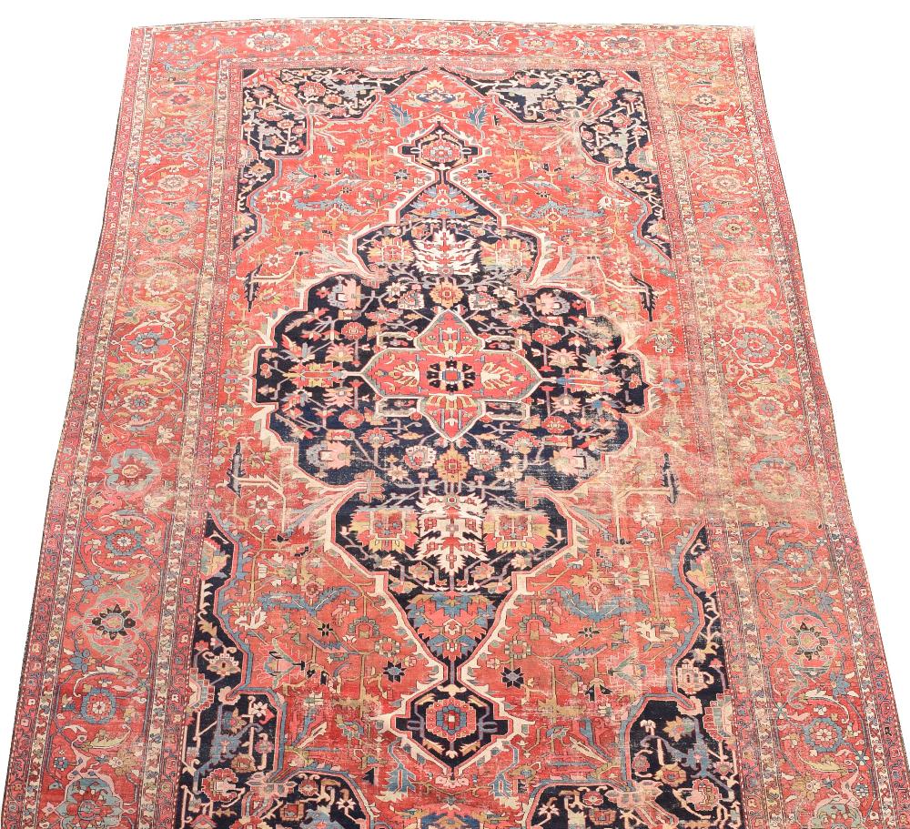 A large Heriz wool carpet, 734 x 485cm (286 x 189in) Worn and holed with end border losses, but well