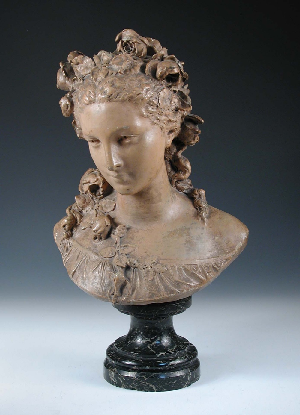 After Albert-Ernest Carrier-Belleuse, a terracotta bust of a young woman with roses in her hair,