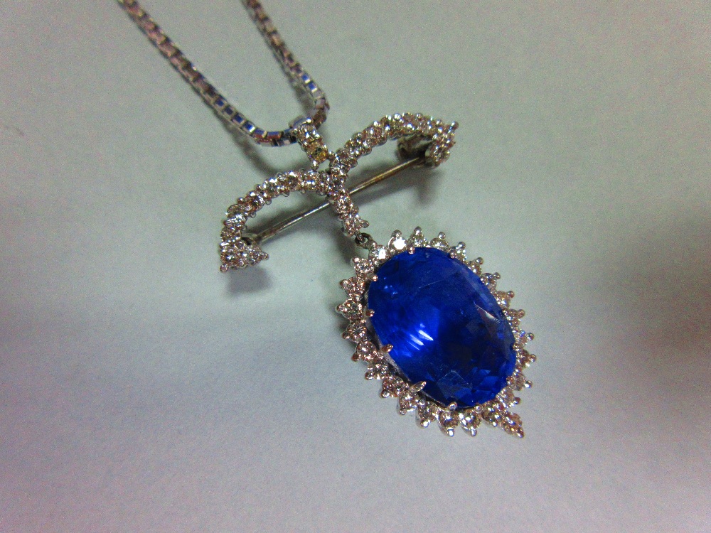 A sapphire and diamond pendant / brooch with white gold chain, the jewel designed as a large oval