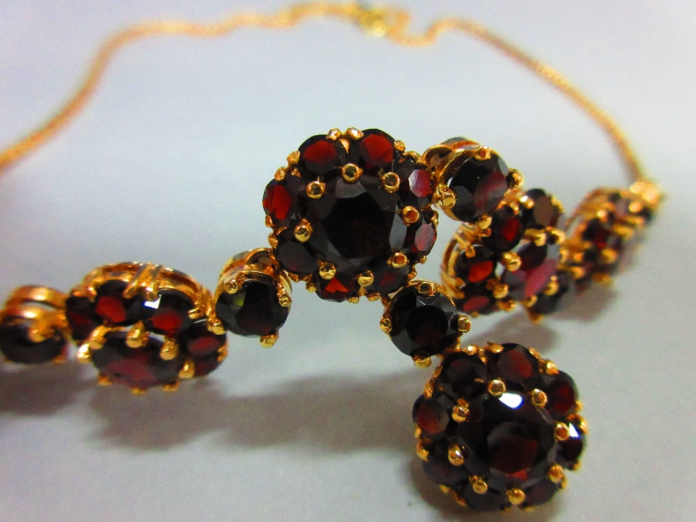 A Bohemian garnet cluster necklace, composed of five flowerhead clusters of round cut garnets, - Image 3 of 4